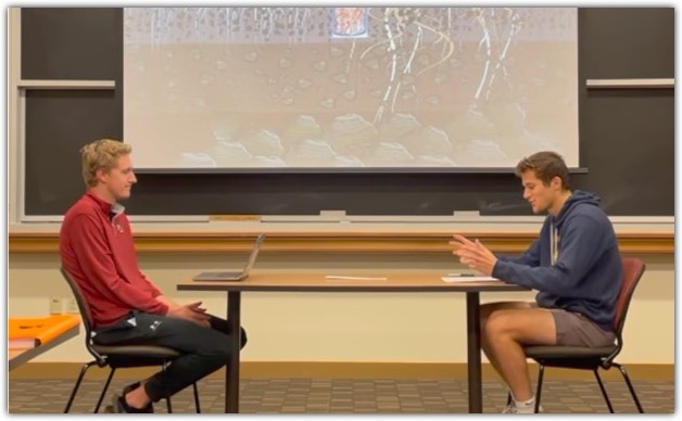 Two students sit across from one another at a table during a mock interview.